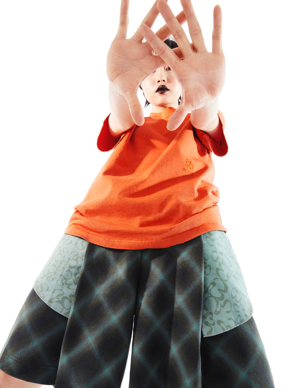 model on a relaxed pose featuring the orange t-shirt with tonal logo emboided